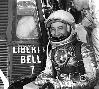 Black and white image of astronaut Gus Grissom by his Liberty Bell 7 spacecraft.