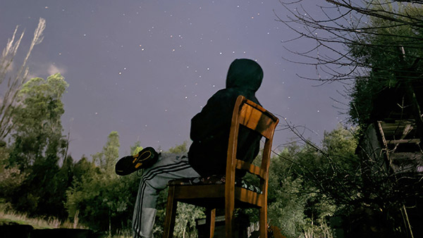 Man sitting in chair in backyard watching the stars.