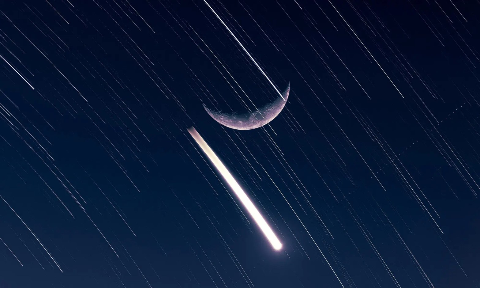 Shows a crescent moon at night beside moving stars.