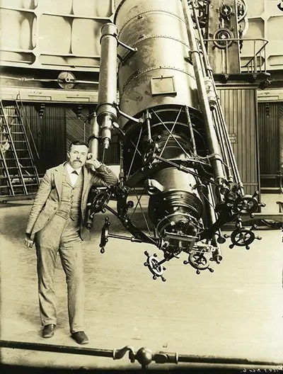 E.E. Barnard standing by a telescope at the Lick Observatory.