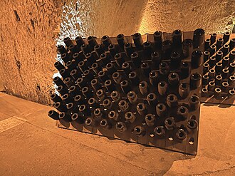 Color photo of bottles on riddling rack in a cellar